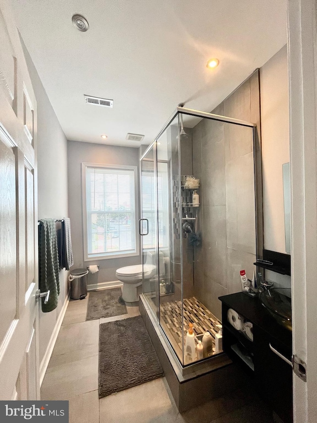 bathroom featuring toilet, a stall shower, and visible vents