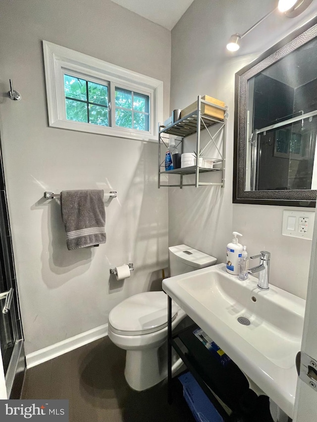 full bathroom featuring toilet, a shower stall, baseboards, and a sink