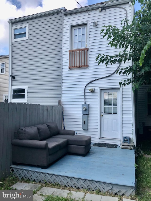 rear view of house featuring a deck, fence, and an outdoor living space