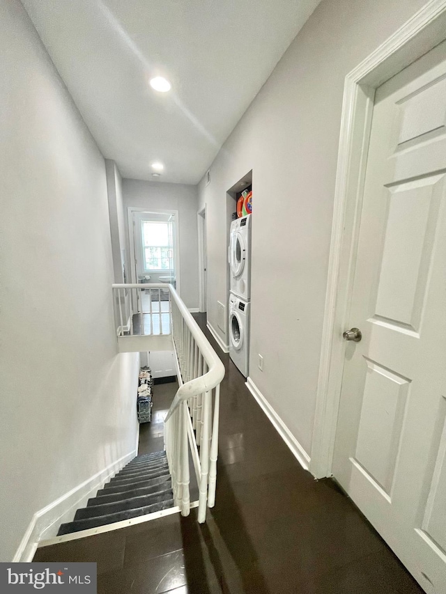 stairs featuring baseboards and stacked washer / dryer