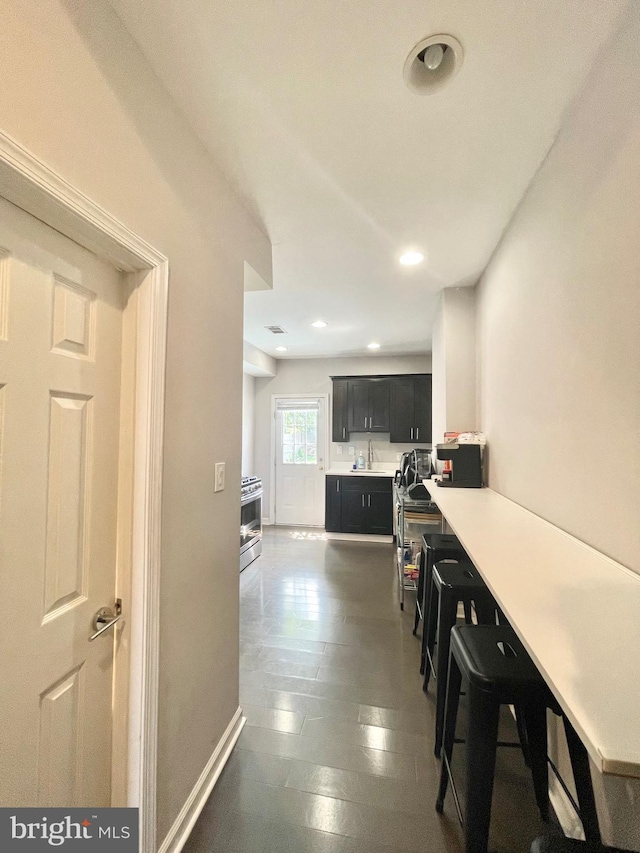 corridor with visible vents, baseboards, a sink, and recessed lighting