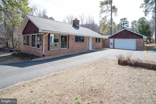 single story home with driveway, an attached garage, a chimney, and brick siding