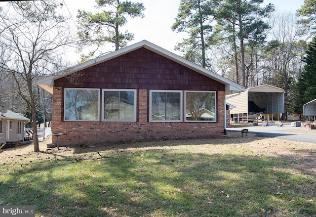 view of side of property with a carport, brick siding, and a yard