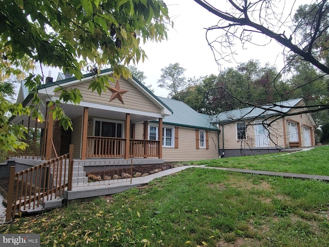 view of front of property featuring a front yard, covered porch, and metal roof