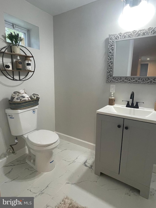 half bath featuring toilet, marble finish floor, and baseboards