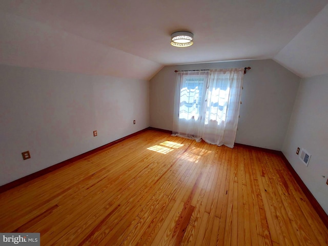 bonus room featuring lofted ceiling, light wood finished floors, baseboards, and visible vents