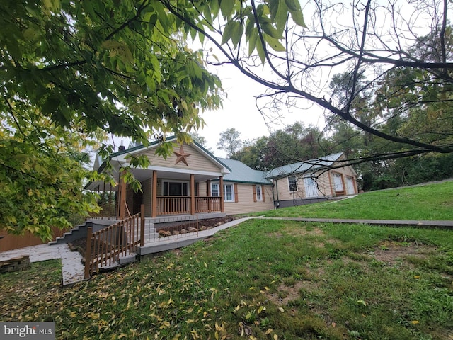 rear view of property with a porch, an outbuilding, a lawn, and stairs