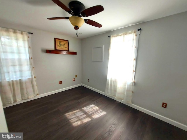 spare room with dark wood-type flooring, ceiling fan, and baseboards