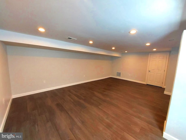 basement featuring dark wood finished floors, visible vents, and baseboards