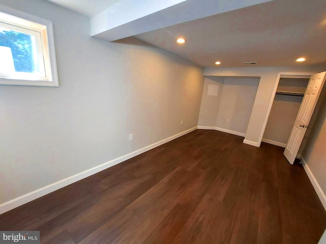 below grade area featuring visible vents, baseboards, dark wood-type flooring, and recessed lighting