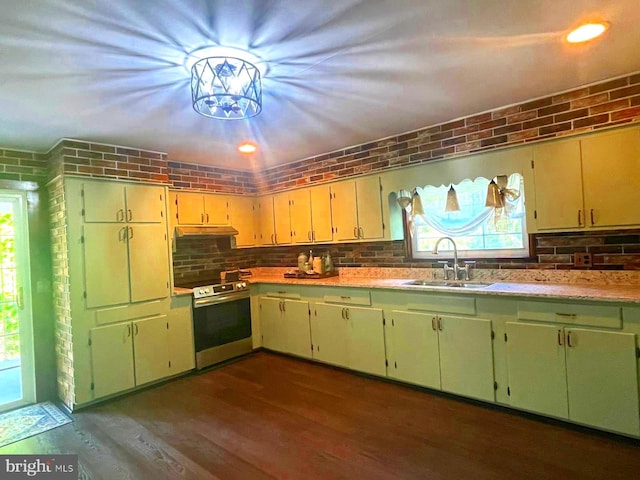 kitchen with a wealth of natural light, electric stove, a sink, and brick wall