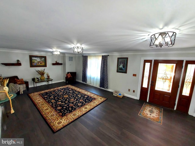 entrance foyer featuring baseboards, ornamental molding, dark wood finished floors, and a notable chandelier