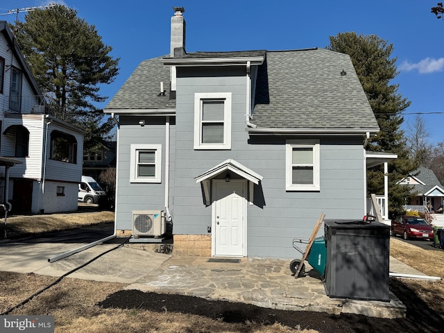 back of house featuring ac unit, a chimney, and roof with shingles