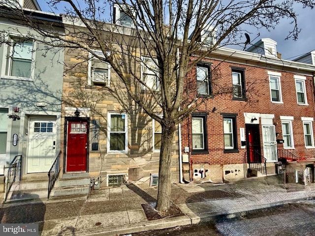 townhome / multi-family property with entry steps, stone siding, and brick siding