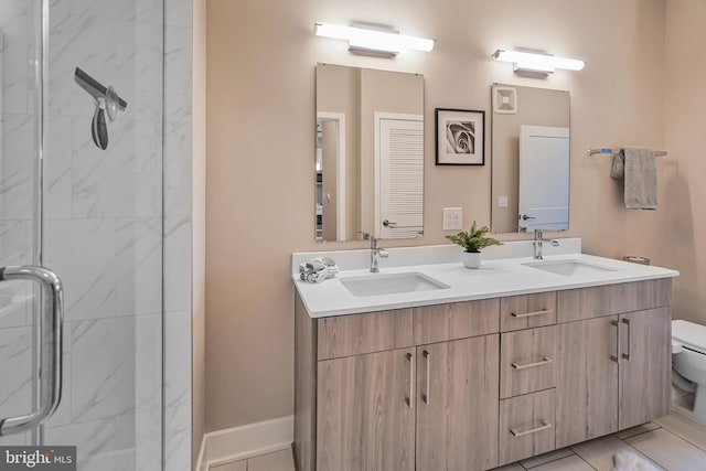 bathroom with toilet, double vanity, a marble finish shower, and a sink