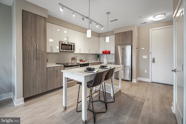 kitchen with stainless steel appliances, light wood-style flooring, backsplash, and visible vents