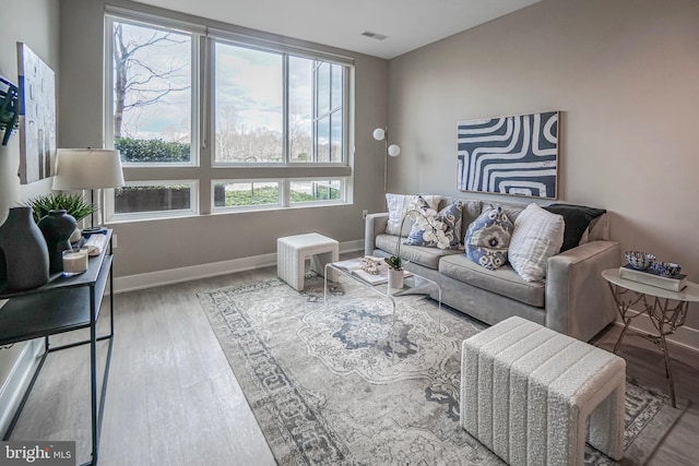 living room featuring visible vents, baseboards, and wood finished floors