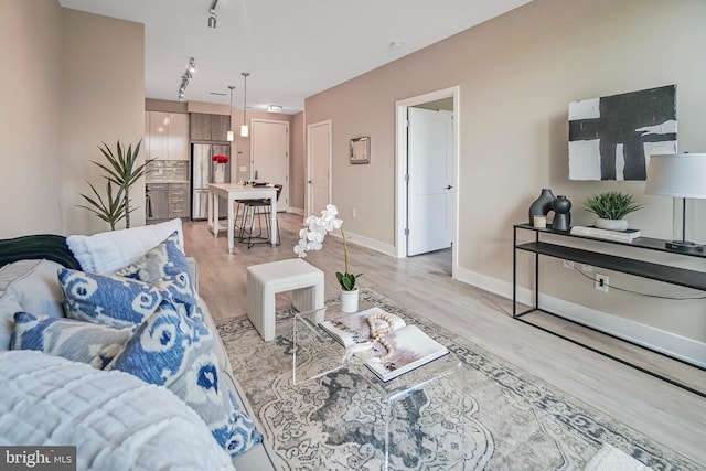 living area featuring light wood-style floors, track lighting, and baseboards