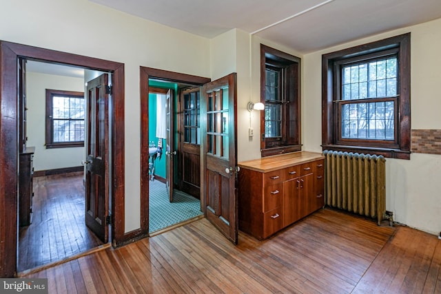 interior space featuring baseboards, hardwood / wood-style floors, and radiator heating unit