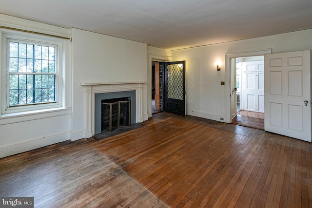 unfurnished living room with wood-type flooring, a fireplace, and baseboards