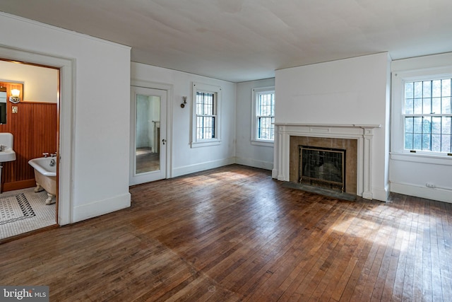 unfurnished living room featuring wood-type flooring, a fireplace, and baseboards