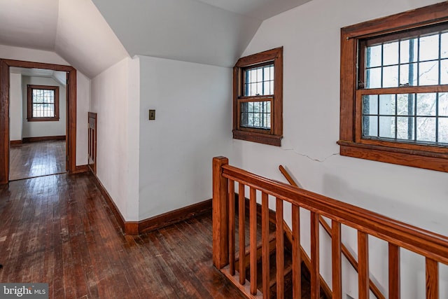 corridor featuring vaulted ceiling, dark wood-type flooring, plenty of natural light, and an upstairs landing