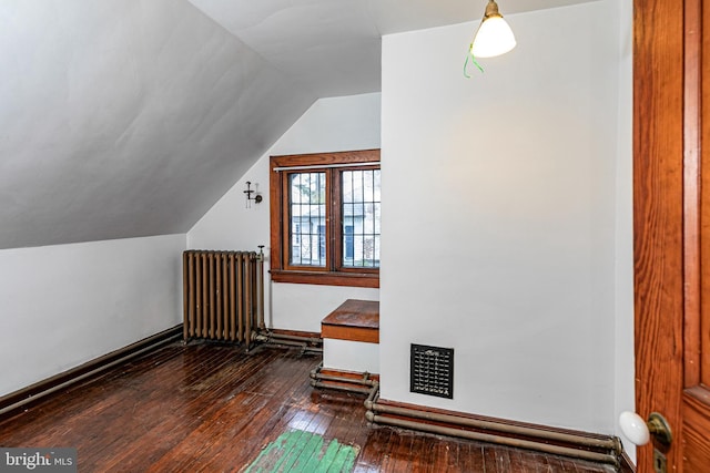 additional living space featuring lofted ceiling, baseboards, hardwood / wood-style flooring, and radiator