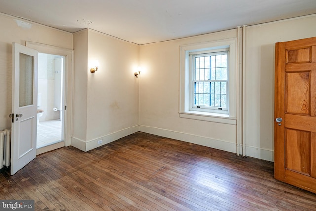 spare room featuring radiator heating unit, baseboards, and hardwood / wood-style floors