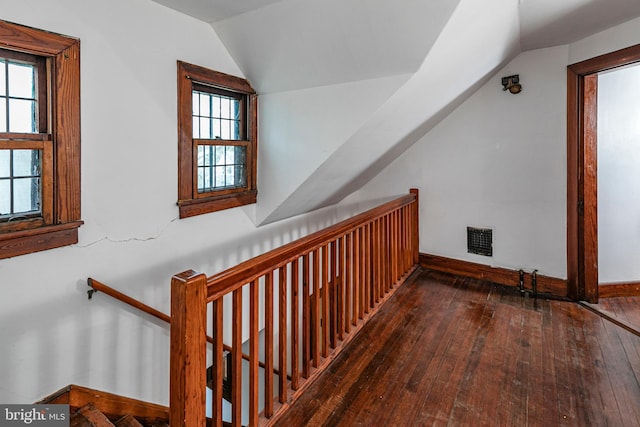 interior space featuring vaulted ceiling, visible vents, hardwood / wood-style flooring, and baseboards