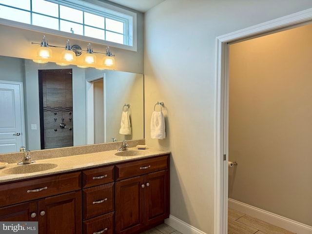 full bathroom with double vanity, baseboards, and a sink