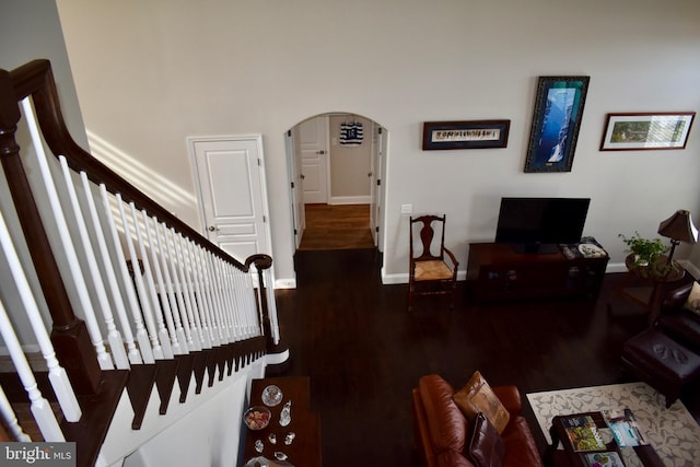 living room with arched walkways, baseboards, and wood finished floors