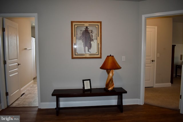 hall with visible vents, baseboards, and wood finished floors