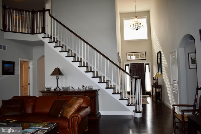 entryway with baseboards, arched walkways, stairway, wood finished floors, and a high ceiling