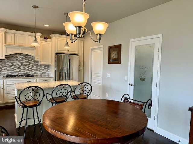 dining room with dark wood-style floors, recessed lighting, an inviting chandelier, and baseboards