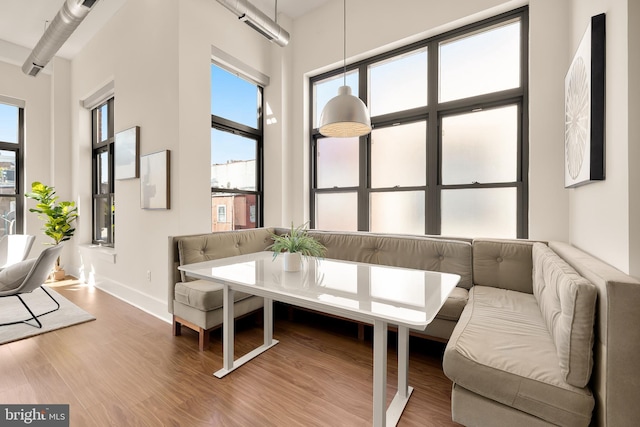 interior space featuring a towering ceiling, baseboards, breakfast area, and wood finished floors