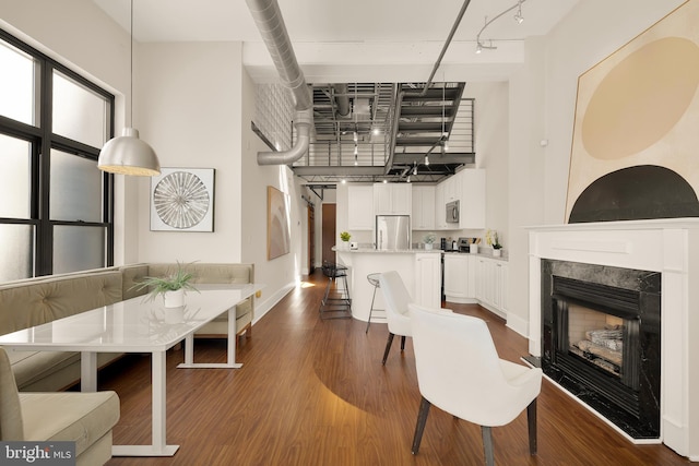 interior space with baseboards, a towering ceiling, dark wood-style floors, a premium fireplace, and rail lighting