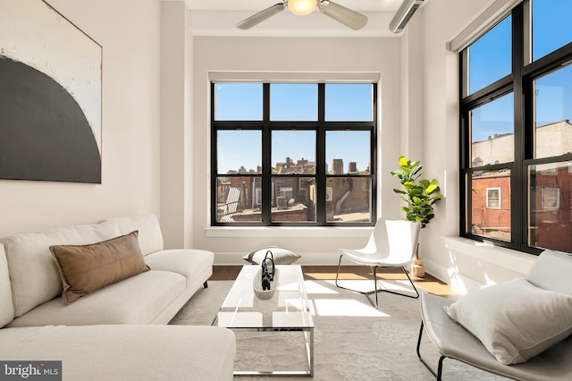 living area featuring a city view, ceiling fan, and baseboards