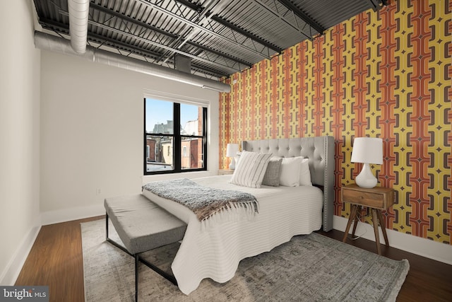 bedroom featuring wallpapered walls, baseboards, and wood finished floors