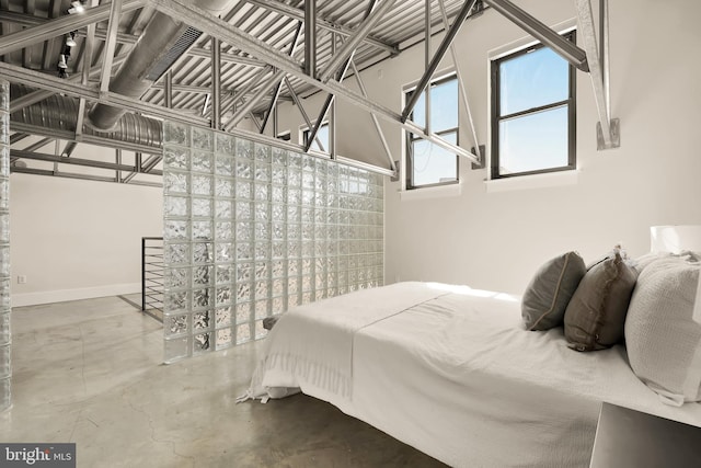 bedroom with finished concrete floors and baseboards