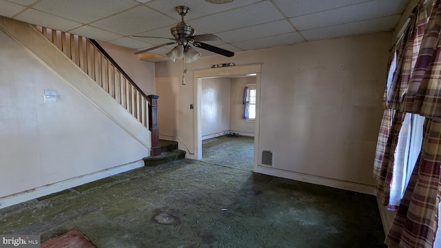 foyer featuring stairs, ceiling fan, a drop ceiling, and baseboards