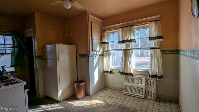 kitchen featuring white appliances, a ceiling fan, and baseboards