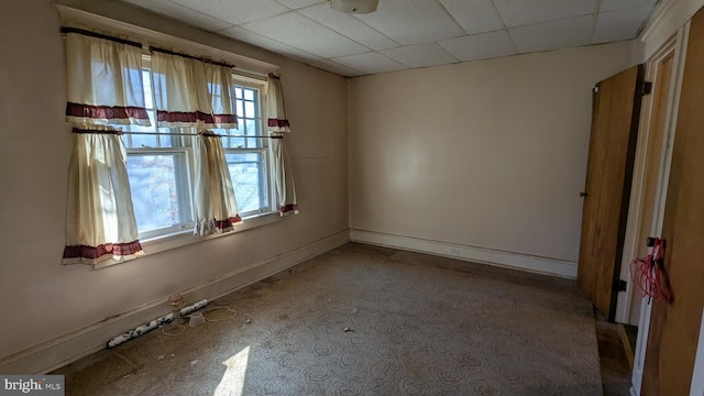 empty room with a paneled ceiling and baseboards