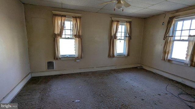 carpeted spare room with baseboards, visible vents, ceiling fan, and a drop ceiling