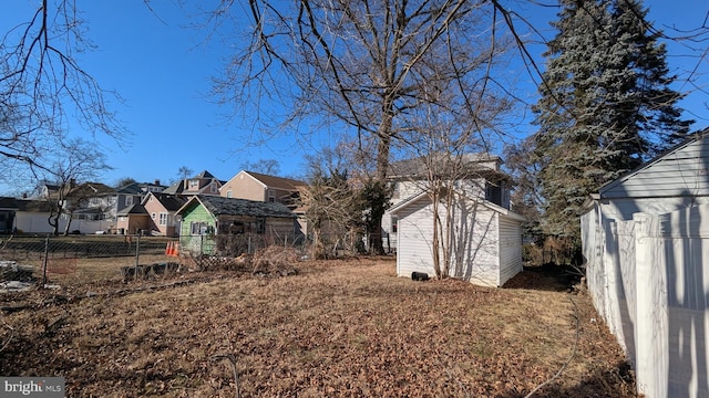 view of yard featuring a residential view, fence, an outbuilding, and a shed