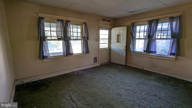 interior space with a paneled ceiling, a healthy amount of sunlight, and visible vents