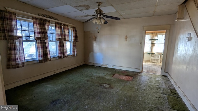 interior space with baseboards, a paneled ceiling, and a healthy amount of sunlight