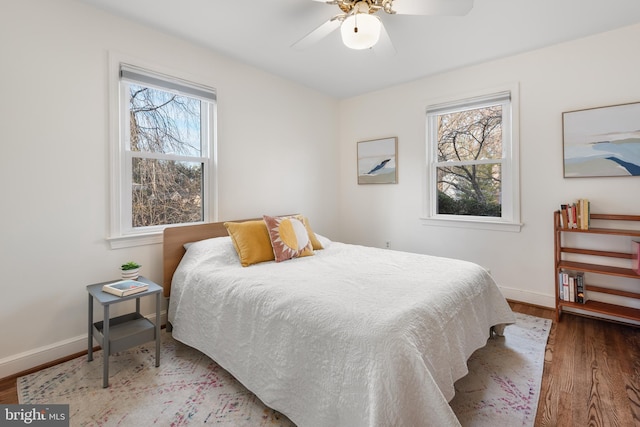 bedroom featuring multiple windows, baseboards, and wood finished floors