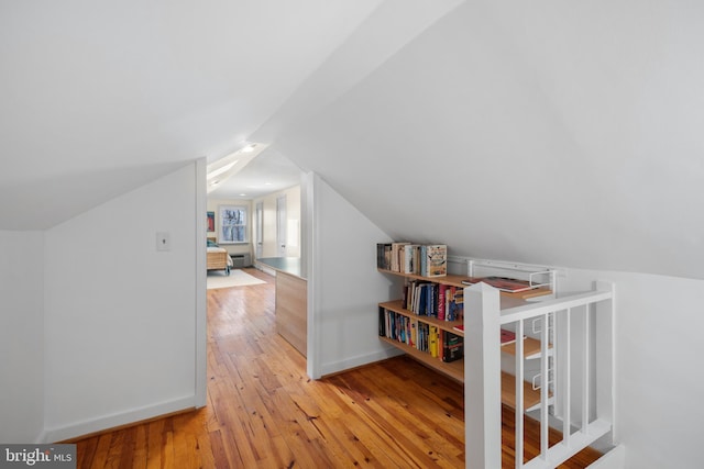 bonus room featuring wood-type flooring, vaulted ceiling, and baseboards