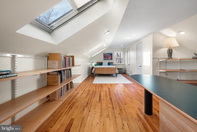 bedroom featuring lofted ceiling with skylight, recessed lighting, wood-type flooring, and a wall mounted AC