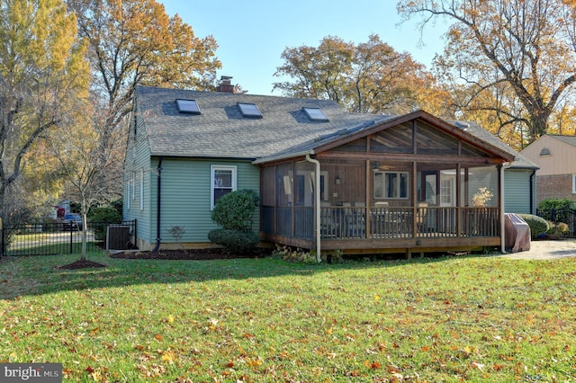 rear view of house featuring roof with shingles, a chimney, a lawn, a sunroom, and fence